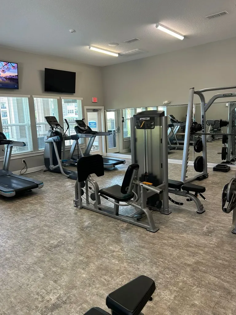 Clean gym area with cardio machines and strength training equipment in an apartment complex clubhouse