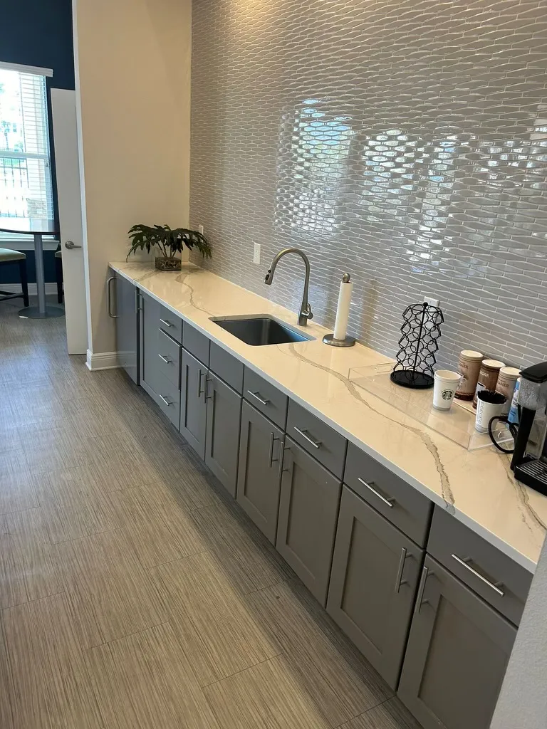 Clean kitchen countertop with a sink and cabinets in an apartment complex clubhouse