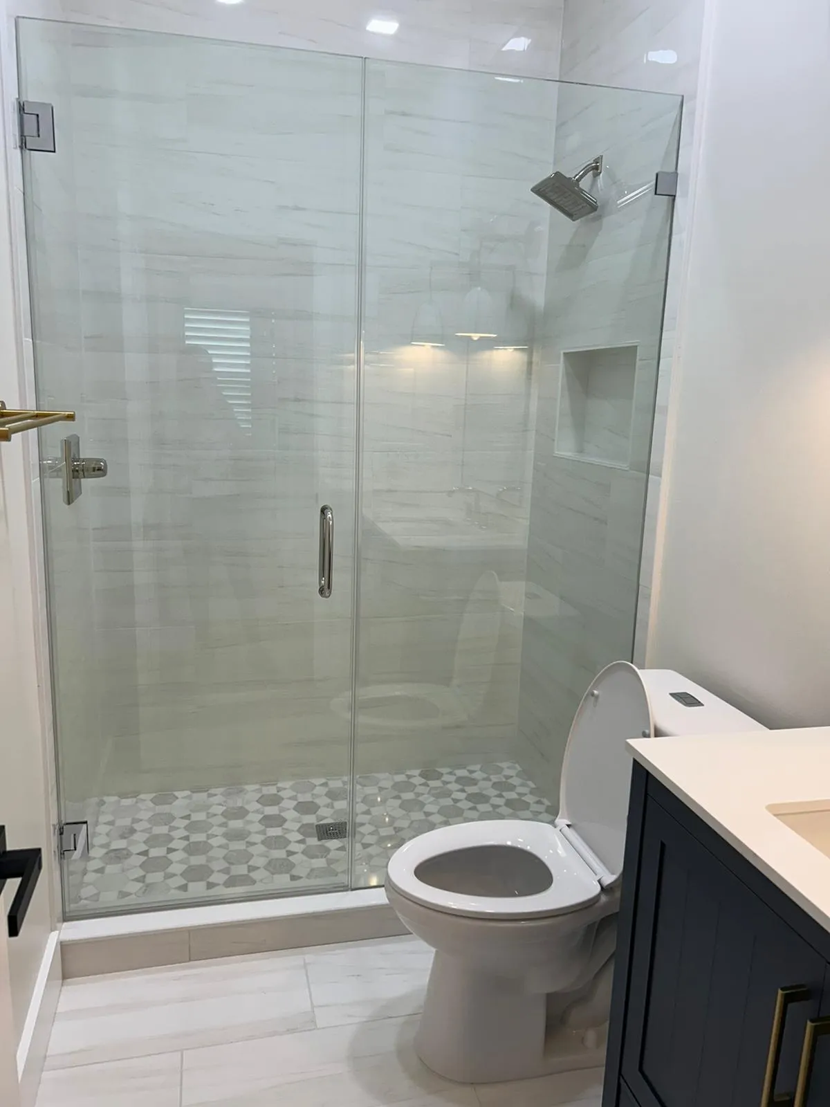 Clean modern white bathroom with a glass shower and toilet in a sleek, minimalist design