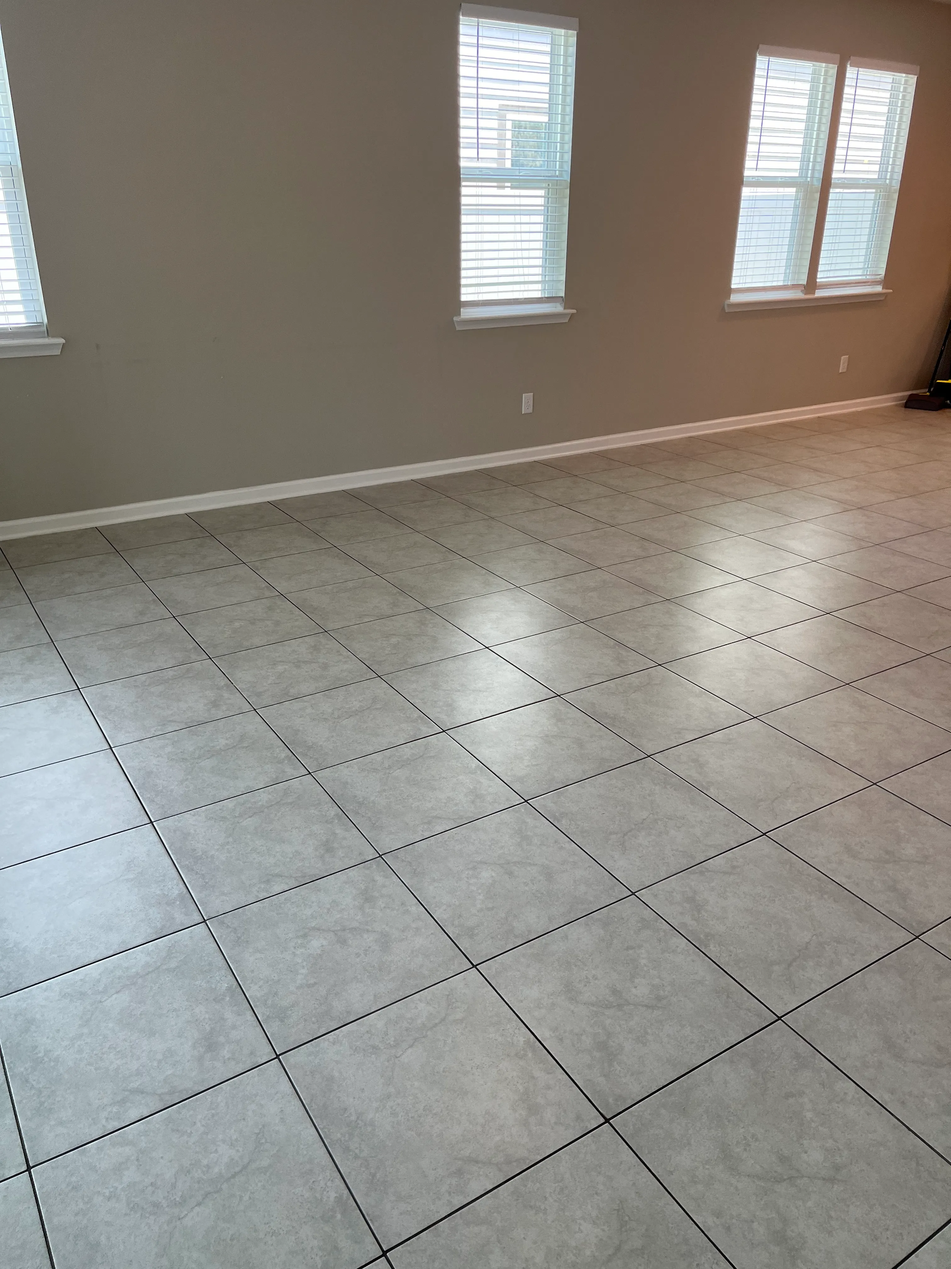 Spacious living room with clean tile flooring and bright windows in a residential home